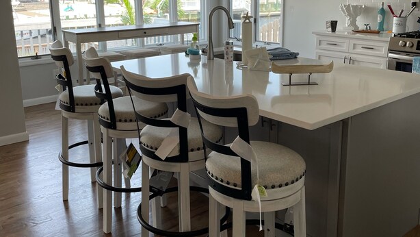 A modern kitchen with a large island, bar stools, and a view of the neighborhood.