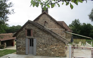 A stone building with a sloped roof, a chimney, and a door.