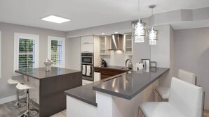 A modern kitchen with a central island, stainless steel appliances, and pendant lighting. - Key Largo Luxury Townhome | Pools & Marina (Key Largo)