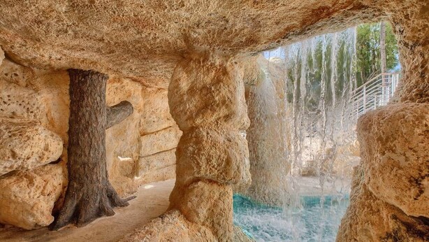 A natural rock formation with a water feature, possibly a hot spring or waterfall, surrounded by stone walls. - Key Largo Luxury Townhome | Pools & Marina (Key Largo)