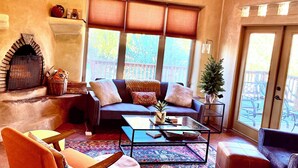 Un salon chaleureux avec une cheminée, des sièges confortables et une vue sur l’extérieur.