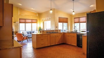 A spacious kitchen with a large island, wooden cabinets, and pendant lighting.