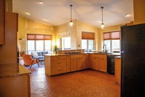 A spacious kitchen with a large island, wooden cabinets, and pendant lighting.