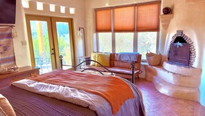 Une chambre à coucher avec un lit, une fenêtre avec des stores, une cheminée et une porte.