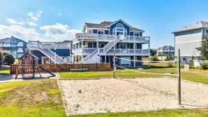 A beachfront property with a large house featuring multiple balconies and a sandy beach area. - Corolla Coastin | 740 ft to the beach | Private Pool, Hot Tub (Corolla)