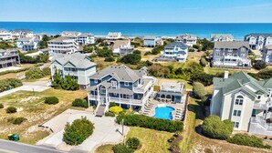 A coastal residential area with houses featuring large front yards, a swimming pool, and a view of the ocean. - Corolla Coastin | 740 ft to the beach | Private Pool, Hot Tub (Corolla)