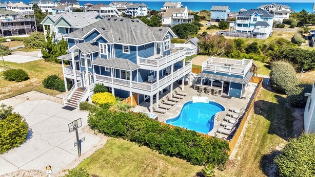 A large two-story house with a swimming pool, surrounded by a well-maintained lawn and a view of the ocean. - Corolla Coastin | 740 ft to the beach | Private Pool, Hot Tub (Corolla)