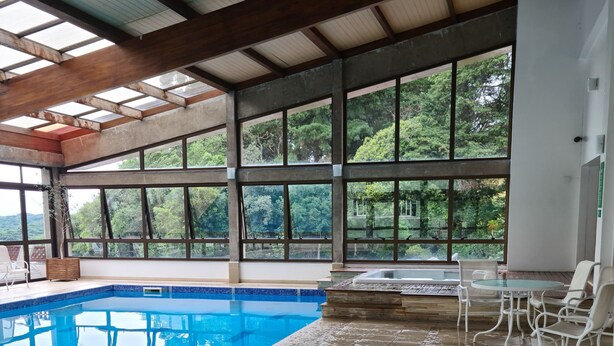 Une piscine intérieure offrant une vue dégagée sur la verdure environnante grâce à de grandes fenêtres.
