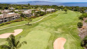 A golf course with bunkers, a water hazard, and a view of the ocean. - Grand Champions in Wailea – Spacious Villa Near Pool w/ Ocean & Sunset Views (Wailea)