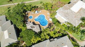 An aerial view of a residential area with a swimming pool surrounded by palm trees and a lawn. - Grand Champions in Wailea – Spacious Villa Near Pool w/ Ocean & Sunset Views (Wailea)