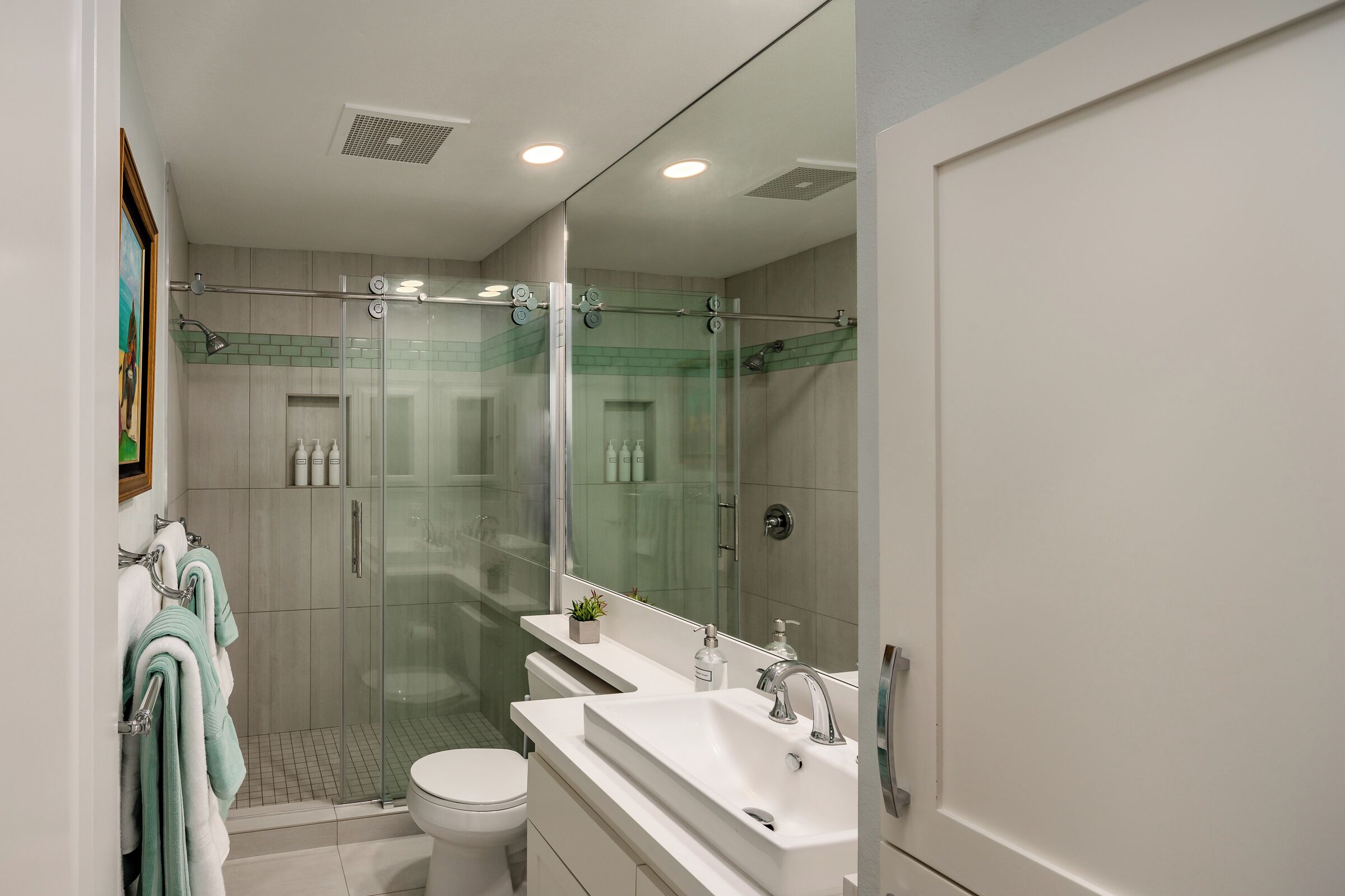 A modern bathroom with a glass-enclosed shower, a white sink, and a toilet.