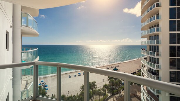 A balcony with a view of the ocean and a beach.