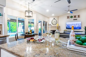 Una cocina moderna con encimera de mármol, un comedor y una sala de estar con televisor.