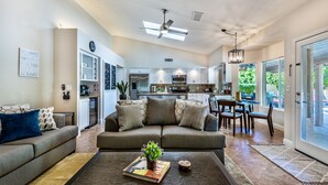 A spacious living room with a sofa, coffee table, and a dining area with chairs and a table.