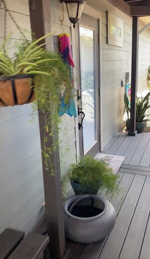 Un porche con una planta en maceta, una jardinera colgante y una maceta hecha con un neumático.