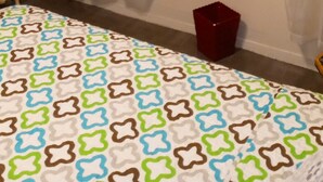 Un dormitorio con una colcha estampada, un cuadro en la pared y un radiador.
