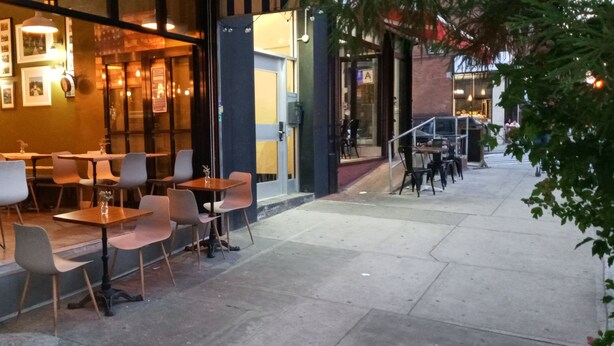 Café al aire libre con mesas y sillas dispuestas para sentarse.