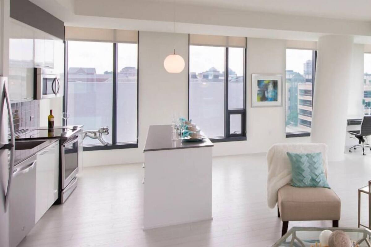 A modern apartment with a kitchen, dining area, and a living room with a sofa and a glass coffee table.