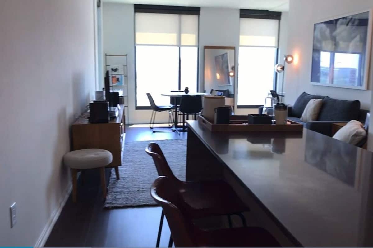 A modern living room with a sofa, a coffee table, and a dining area with chairs and a table.