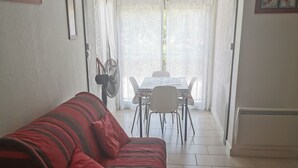 Ein Wohnzimmer mit einem rot-gestreiften Sofa, einem Esstisch mit Stühlen und einem Ventilator.