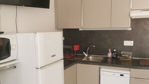 Eine moderne Küche mit weißen Geräten, einem Flachbildfernseher und beigen Schränken.