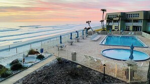 A beachfront hotel with a pool area, beach access, and a view of the ocean.