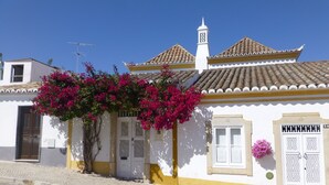 Un edificio tradicional con techo de tejas, fachada blanca y una pequeña torre de campanas.