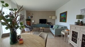 Una sala de estar con televisor, sofá y comedor.