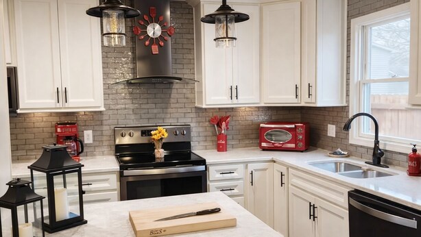 A kitchen with white cabinets, a black stove, a red toaster, and a black range hood. - The Illini Game House (Champaign)