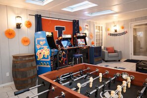 A room with a foosball table, arcade games, and a cozy seating area.