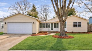 A two-story house with a garage, a well-maintained lawn, and a mature tree in the front yard. - The Illini Game House (Champaign)