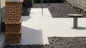 A patio area with a brick fireplace, a seating bench, and a small table. - Casa do Caminho (Praia da Vitoria)