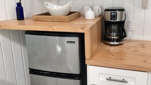 A compact kitchen with a stainless steel refrigerator, a wooden countertop, a coffee maker, and a plant. - Sun Filled, Tropical Bungalow (Haleiwa)