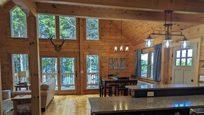 L’intérieur d’une cabane en bois comprend une cuisine, un coin repas et de grandes fenêtres.