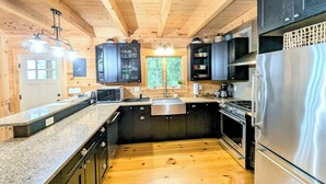 Une cuisine moderne avec des poutres en bois, des comptoirs en granit, des appareils électroménagers en acier inoxydable et des armoires noires.
