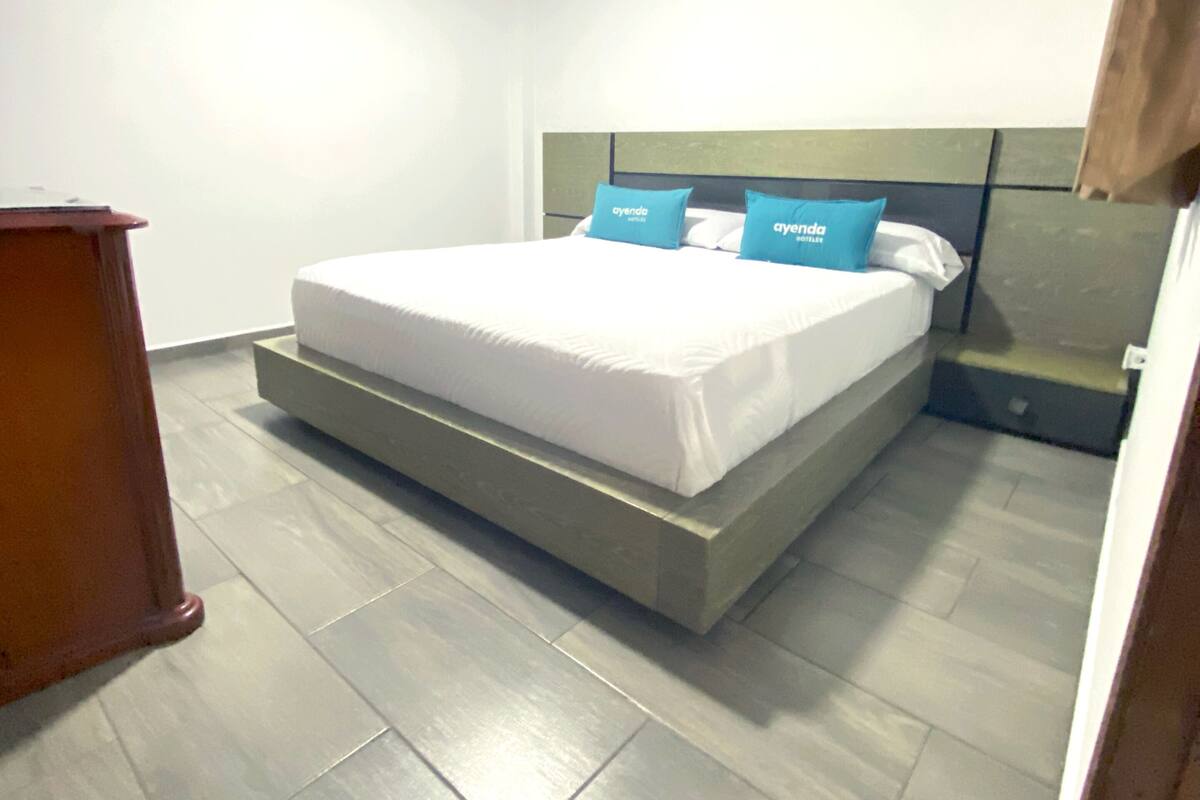 Un dormitorio moderno con una cama grande, una mesita de noche y un aparador de madera.