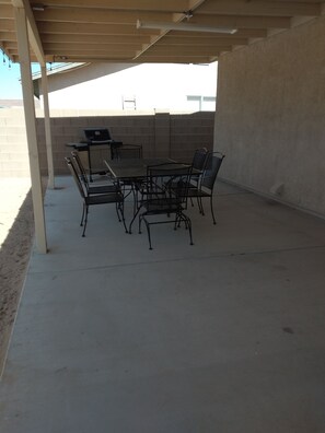 An outdoor patio with a table and chairs, a grill, and a concrete floor. - Comfy Retreat  (Yuma)
