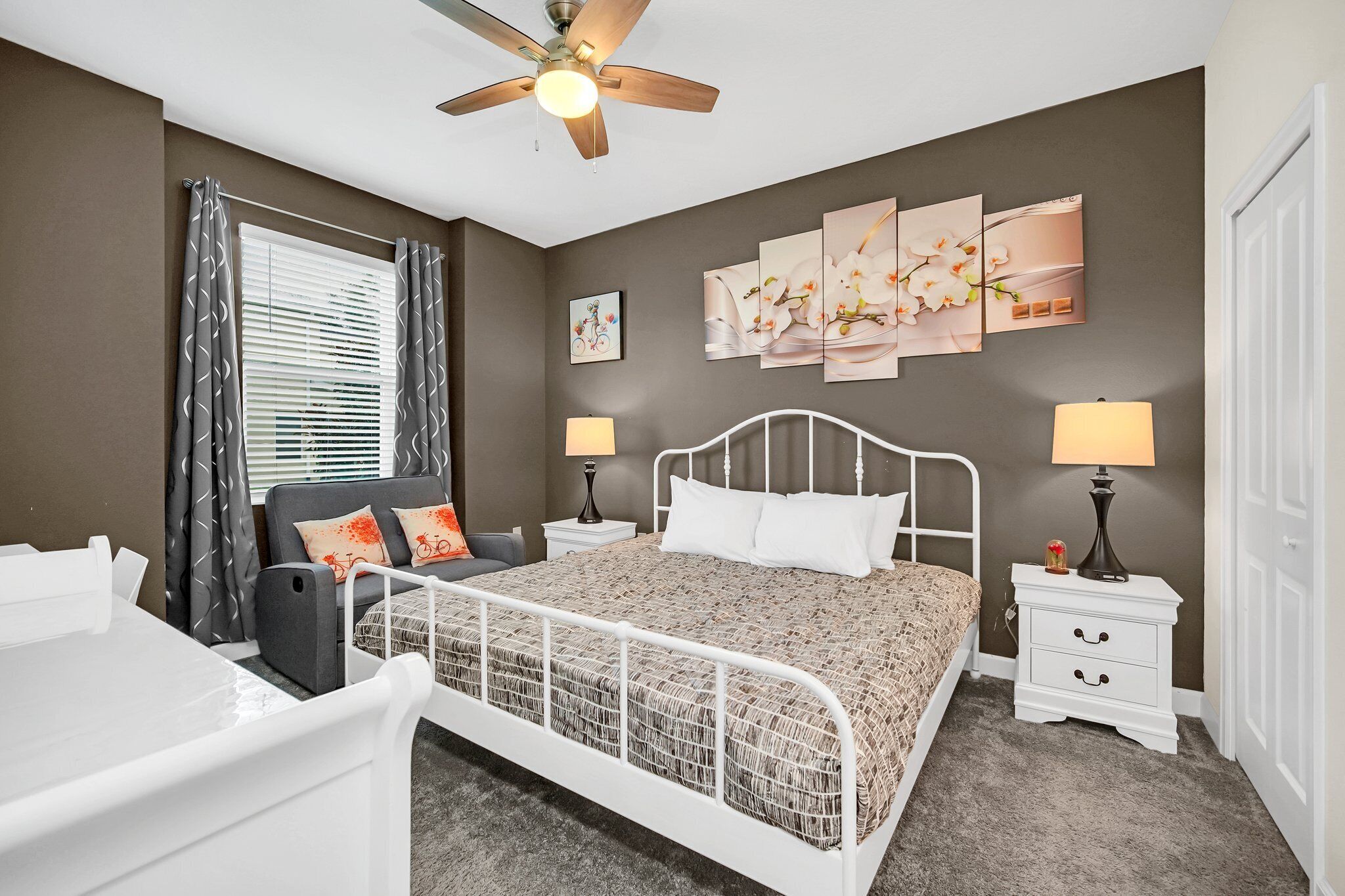 A bedroom with a bed, bedside tables, a ceiling fan, and artwork on the wall.