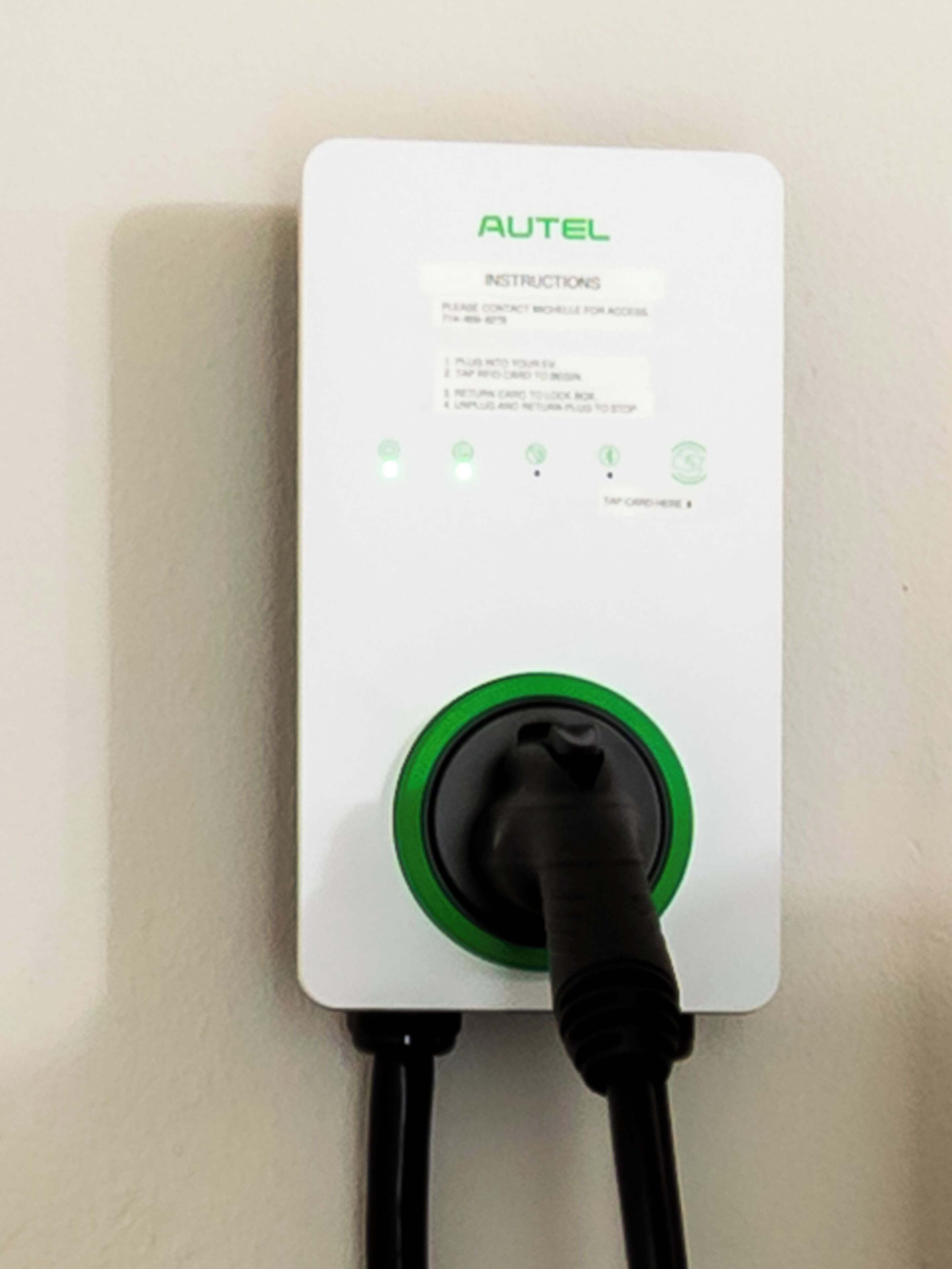 An AUTEL charging station with instructions and a green plug.