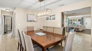 A dining area with a wooden table, six chairs, and a modern chandelier.