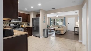 A modern kitchen with dark cabinets, stainless steel appliances, and a tiled floor.