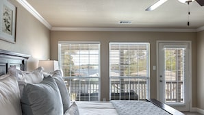 Une chambre à coucher avec un lit, une table de chevet, une lampe et une fenêtre avec des stores.