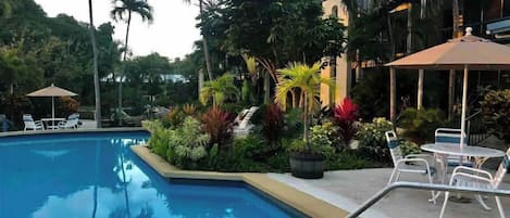 A swimming pool surrounded by lush greenery and outdoor seating areas.