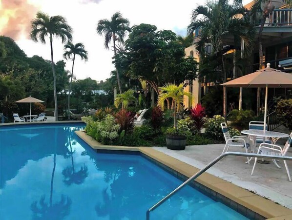A swimming pool surrounded by lush greenery and outdoor seating areas.