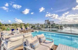 Area piscina sul tetto con sedie a sdraio e vista panoramica sulla città.