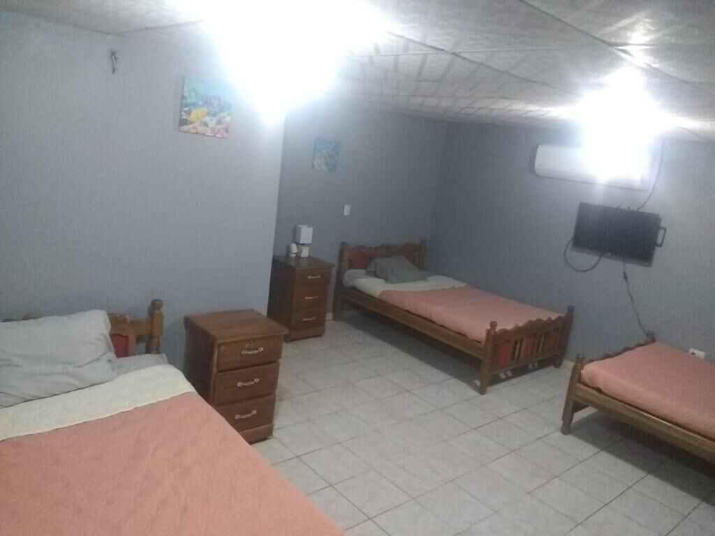 A bedroom with two beds, a dresser, a bedside table, and a wall-mounted TV.