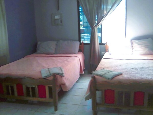 A room with two single beds, a small table, and a window with curtains.