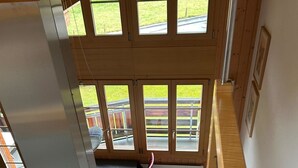 Una cocina con extractor de acero inoxidable, encimera negra y vistas a una terraza de madera a través de amplios ventanales.