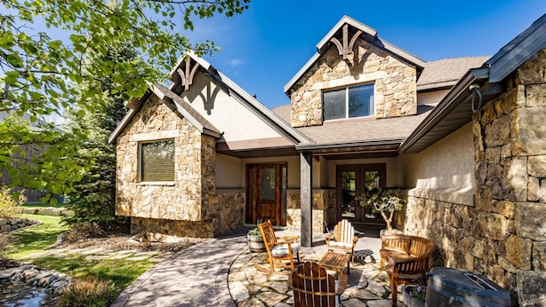 A stone house with a stone exterior, a covered porch, and a stone patio with outdoor furniture. - Luxury home with breathtaking  views, 10 min. to Mayflower Resort, 15 to gondola (Heber City)