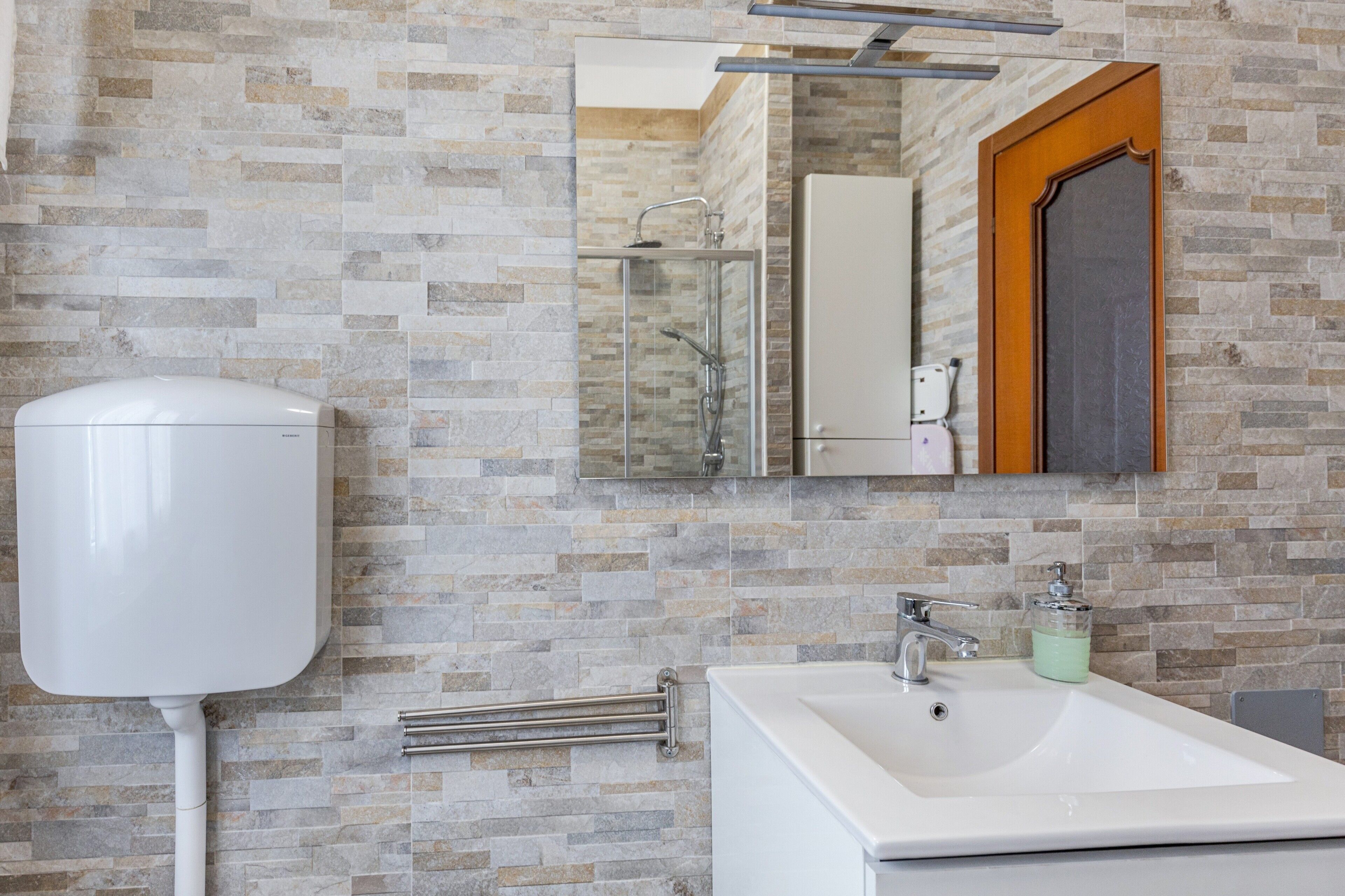 A bathroom with a toilet, a sink, a mirror, and a shower.